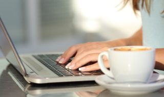Woman hands typing in a laptop in a coffee shop
