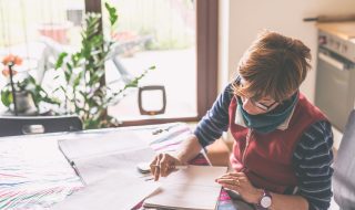 Woman working at home, reading and handwriting documents
