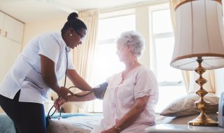 Nurse checking blood pressure of female patient